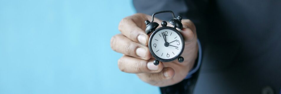 a man in a suit holding a small alarm clock